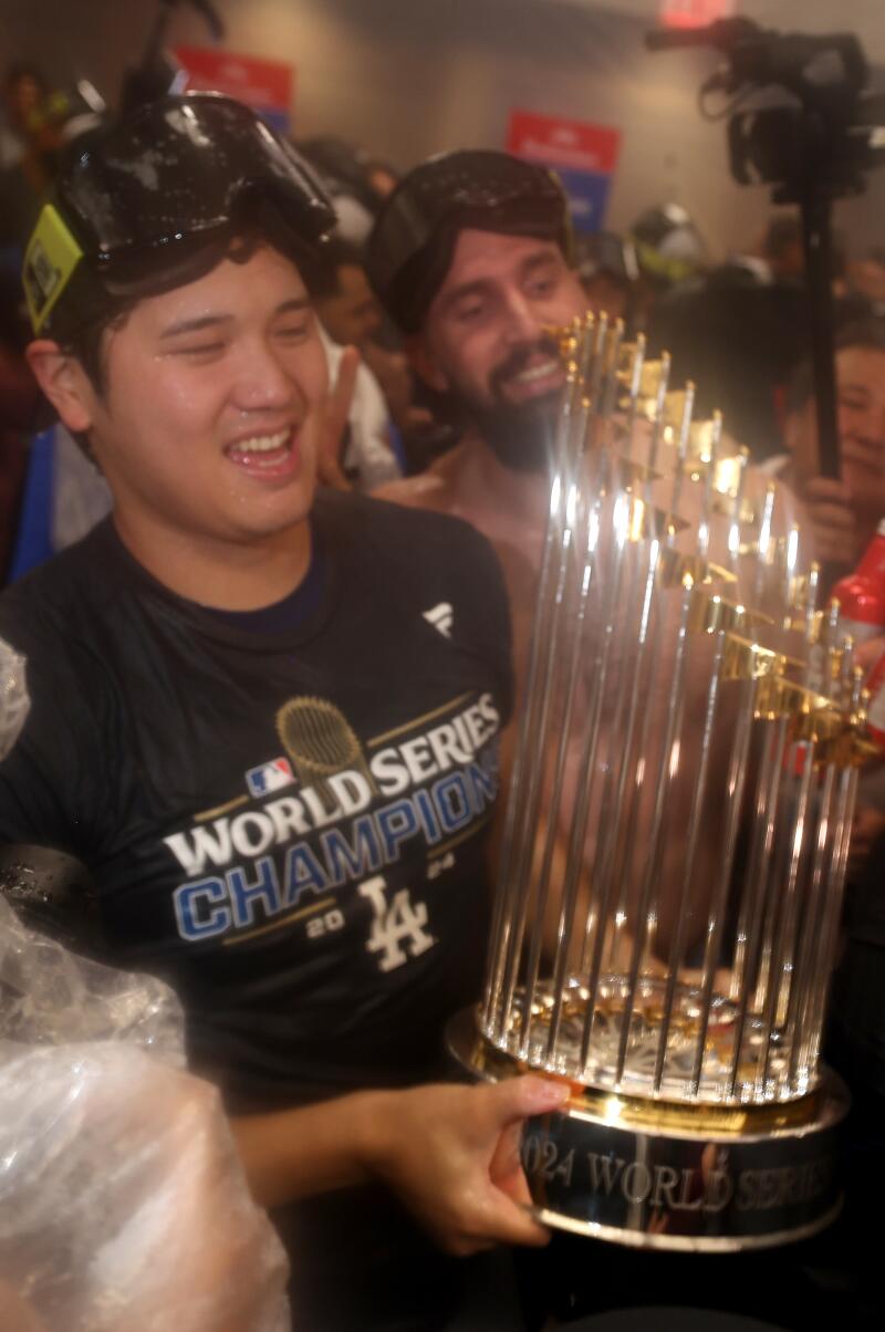 Dodgers star Shohei Ohtani celebrates in the locker room with his teammates while holding the World Series trophy following their win over the Yankees.