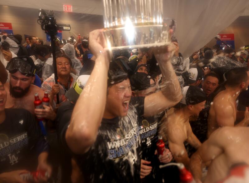 BRONX, NEW YORK - OCTOBER 30, 2024: Los Angeles Dodgers two-way player Shohei Ohtani (17) holds the World Series trophy in the locker celebration. Game 5 of the World Series against the Yankees at Yankees Stadium in New York City Wednesday, October 30 2024. (Robert Gauthier/Los Angeles Times)