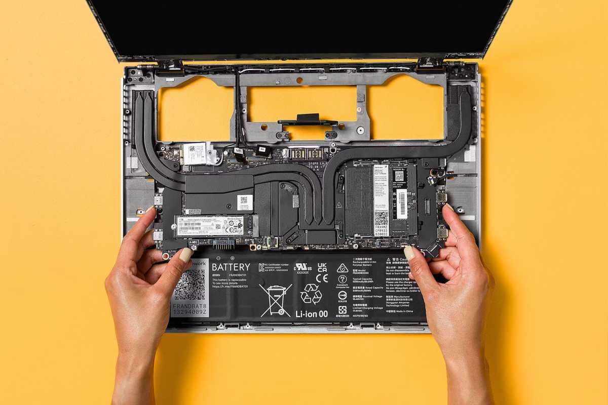 Framework laptop with open internals on a yellow background