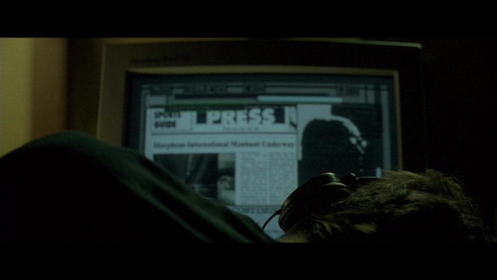 Neo sleeps while a tool on his computer downloads and searches newspaper articles.